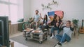 Multi ethnic group of friends with USA national flags watching sport championship on TV together cheering up their Royalty Free Stock Photo