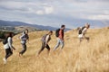 Multi ethnic group of happy young adult friends climbing a hill during a mountain hike, side view