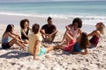 Multi-ethnic group of male and female sitting on the beach Royalty Free Stock Photo