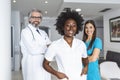 A multi-ethnic group of three doctors and nurses standing in a hospital corridor, wearing scrubs and coats. The team of healthcare Royalty Free Stock Photo