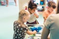 Multi-ethnic group of toddlers milk painting with the teacher helping them, using food coloring for colors. Children Royalty Free Stock Photo