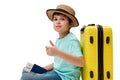 Multi-ethnic teenage boy in blue t-shirt and straw hat with suitcase and boarding pass, shows thumb up looking at camera Royalty Free Stock Photo