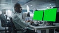 Multi-Ethnic Office: Black IT Programmer Working on Computer with Green Screen Chroma Key Display Royalty Free Stock Photo