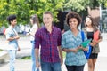 Multi ethnic student couple walking and talking in city Royalty Free Stock Photo