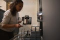 Multi ethnic woman, housewife unloading a clean stainless saucepan from a dishwasher. Modern kitchen appliances Royalty Free Stock Photo