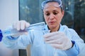 Multi-ethnic woman laboratory assistant pouring liquid from a graduated cylinder into a test tube through a lab funnel Royalty Free Stock Photo