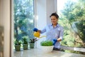 Multi-ethnic woman waters houseplants and cultivated culinary herbs. Good hobby, clean air at home, housekeeping concept