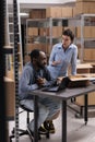 Multi ethnic workers analyzing client delivery data on laptop computer after putting clothes order in cardboard box Royalty Free Stock Photo