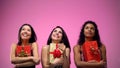 Multi-ethnic young ladies holding presents and looking up, holiday celebration