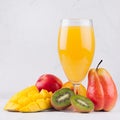 Multi fruit tropical juice in elegant glass with different fruits on white wood board, square. Royalty Free Stock Photo