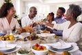 Multi-Generation Family Celebrating Christmas At Home Eating Meal And Making Toast With Wine