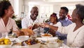 Multi-Generation Family Celebrating Christmas At Home Eating Meal And Making Toast With Wine Royalty Free Stock Photo