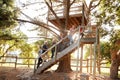 Multi-Generation Family Climbing Outdoor Wooden Platform To Tree House In Garden