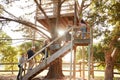 Multi-Generation Family Climbing Outdoor Wooden Platform To Tree House In Garden