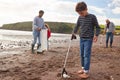 Multi-Generation Family Collecting Litter On Winter Beach Clean Up