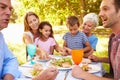 Multi-generation family eating together outdoors