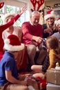 Multi-Generation Family Exchanging And Opening Gifts Around Christmas Tree At Home Royalty Free Stock Photo