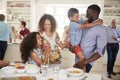 Multi-Generation Family And Friends Gathering In Kitchen For Celebration Party