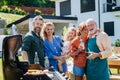 Multi generation family grilling outside on backyard in summer during garden party Royalty Free Stock Photo