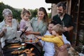 Multi generation family grilling outside on patio in summer during garden party Royalty Free Stock Photo