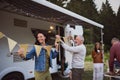 Multi-generation family preparing party by car outdoors in campsite, caravan holiday trip. Royalty Free Stock Photo