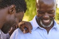 Multi-Generation Family With Senior Father And Adult Song Standing And Laughing In Garden Together