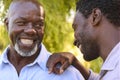 Multi-Generation Family With Senior Father And Adult Song Standing And Laughing In Garden Together