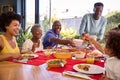 Multi-Generation Family Sitting Around Table At Home Enjoying Meal Together Royalty Free Stock Photo