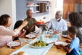 Multi-Generation Family Sitting Around Table At Home Enjoying Meal Together Royalty Free Stock Photo