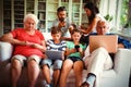 Multi-generation family sitting on sofa and using various technologies