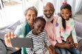 Multi-generation family taking selfie with mobile phone on a sofa in living room Royalty Free Stock Photo