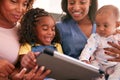 Multi-Generation Female African American Family Sitting On Sofa At Home Using Digital Tablet Royalty Free Stock Photo