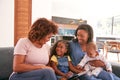 Multi-Generation Female African American Family Sitting On Sofa At Home Using Digital Tablet Royalty Free Stock Photo