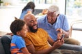 Multi-Generation Male African American Family On Sofa At Home Laughing At Mobile Phone