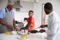 Multi Generation Male Family In Kitchen At Home Making Pancakes Together