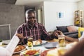 Multi-generational African-American family saying grace at dinner table and holding hands