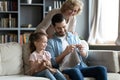 Multi-generational family enjoy common hobby knitting seated on couch Royalty Free Stock Photo