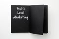 Multi Level Marketing written in notebook with black pages on white background, top view