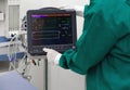 Multi-parameter patient monitor in operating room, controlled by nurse in surgical green gown uniform