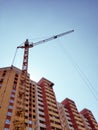 A multi-storey brick house under construction and a tower crane on a background of blue sky. Royalty Free Stock Photo