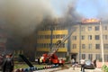 A multi-storey building is on fire and there are fire trucks nearby to extinguish the fire