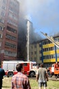 A multi-storey building is on fire and there are fire trucks nearby to extinguish the fire