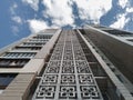 Multi-storey concrete residential building with shaped windows. Bottom-up view of the facade