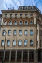 A multi-story building with a decorated facade featuring rows of arched windows, contrasting textures, and a dark-colored upper Royalty Free Stock Photo