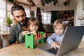 Multi-tasking freelance and fatherhood concept. Working single father with kids and laptop computer Royalty Free Stock Photo