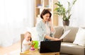 Working mother with baby calling on smartphone