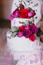 Multi tiered beautiful wedding cake with white cream decorated with pink and red roses and eucalyptus Royalty Free Stock Photo