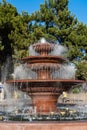 Multi-tiered musical `Singing` fountain. Pool and bowls of fountain are made of red granite. Jets of water fly out of nozzles Royalty Free Stock Photo