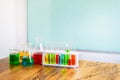 Multicolor chemical in glass test tube on plastic stand and beaker on wood table. with copy space