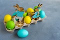 Multicolor easter eggs with easter bunnies in egg carton on grey background Royalty Free Stock Photo